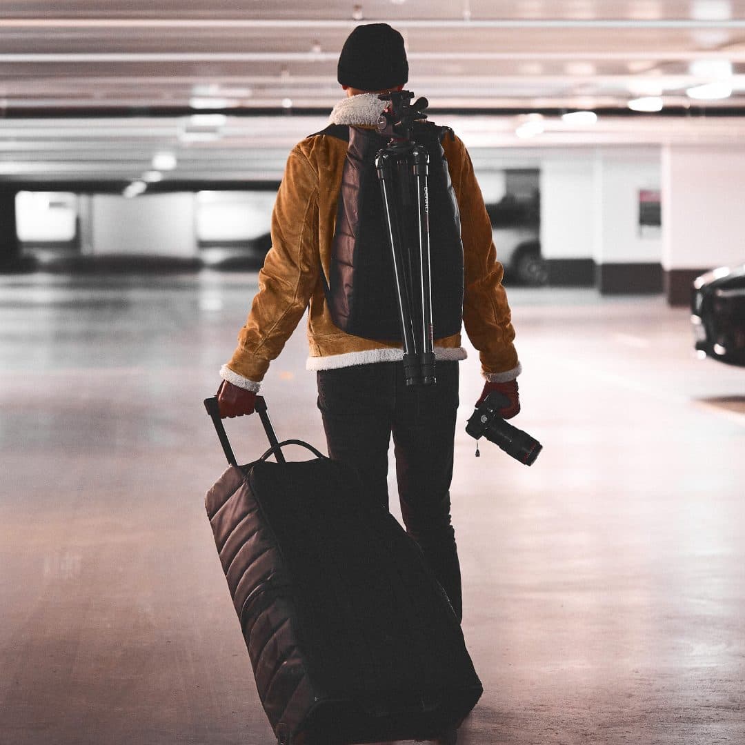 Fotograf på vei inn til opptak med stativ, kamera og utstyrskoffert